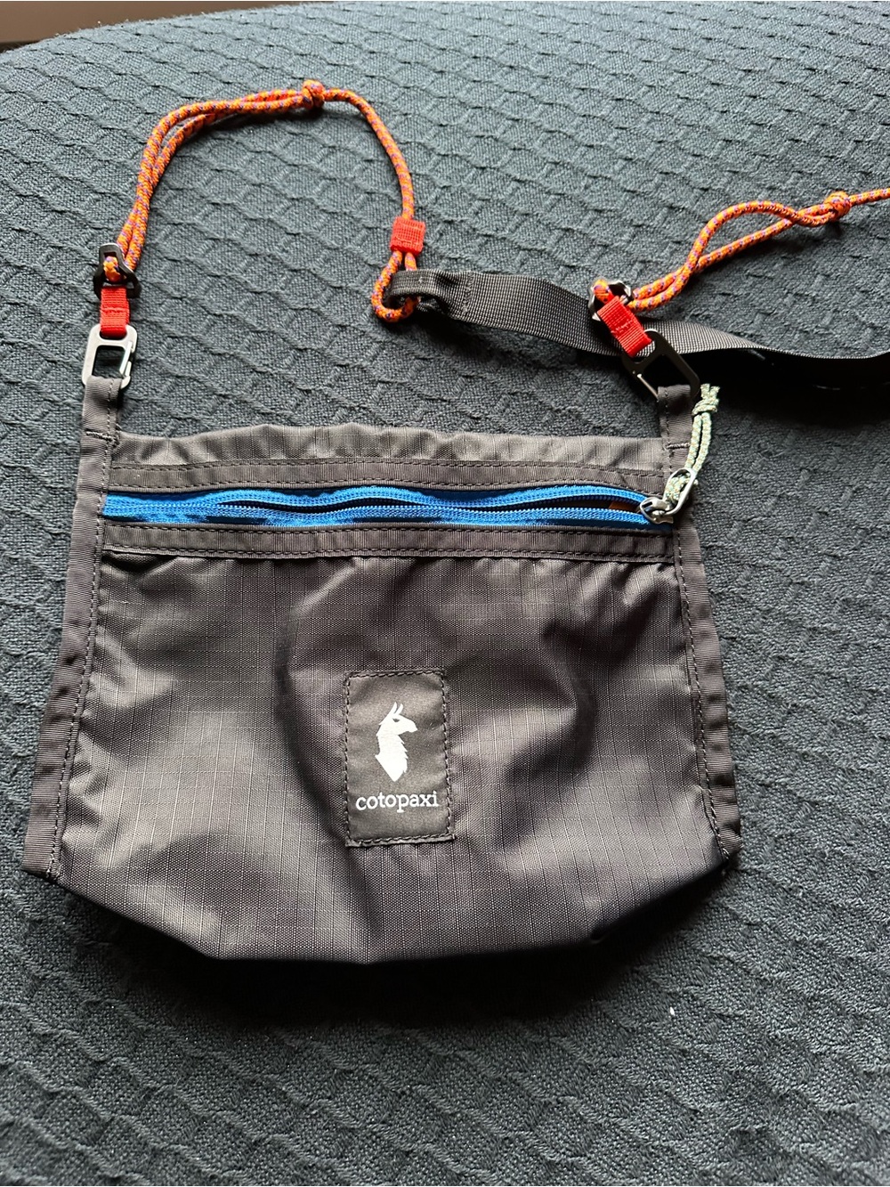 cotopaxi Black Crossbody Bag with Blue Zipper and Orange Strap Accents